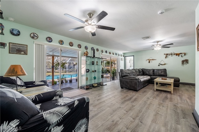 living area with light wood-type flooring, baseboards, visible vents, and a ceiling fan