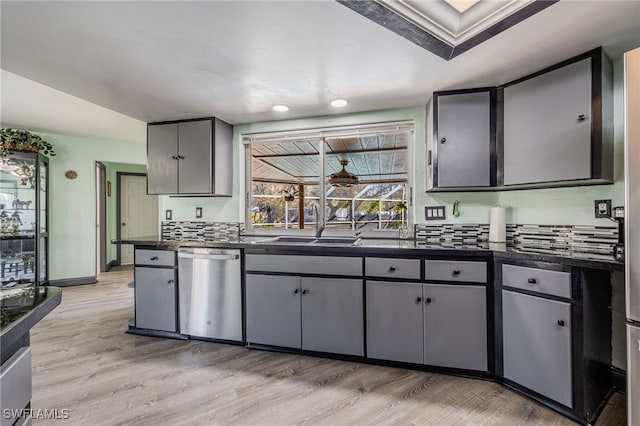 kitchen featuring gray cabinets, tasteful backsplash, dishwasher, sink, and light wood-type flooring