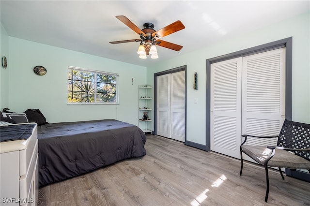 bedroom with ceiling fan, light hardwood / wood-style flooring, and two closets