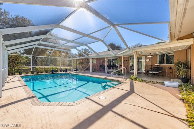 pool with glass enclosure, a patio area, and a ceiling fan