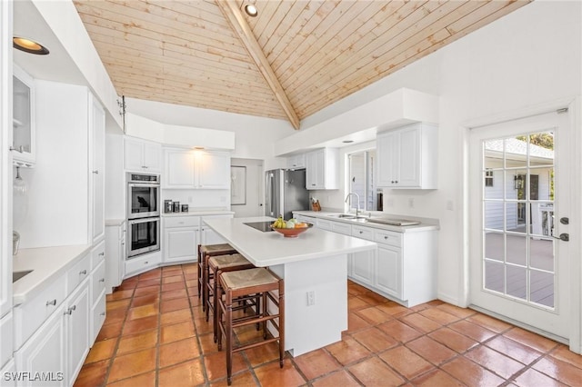 kitchen with wood ceiling, appliances with stainless steel finishes, white cabinetry, a kitchen breakfast bar, and a center island