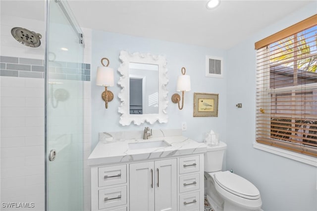 bathroom featuring vanity, toilet, and a shower with shower door