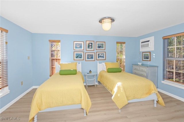 bedroom featuring a wall unit AC and light hardwood / wood-style flooring