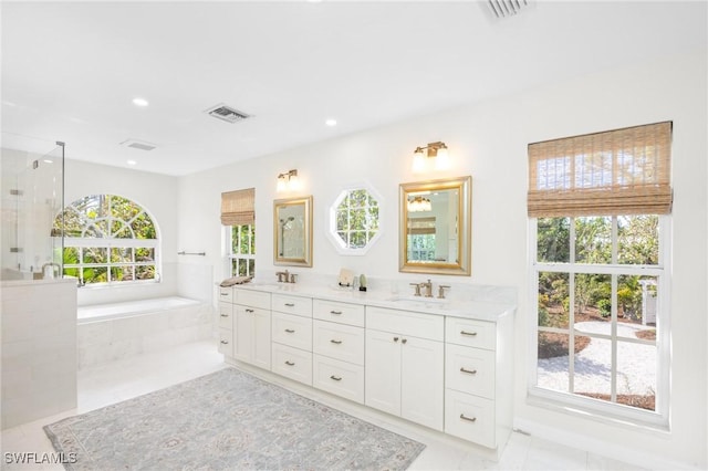 bathroom with tile patterned flooring, vanity, and a relaxing tiled tub