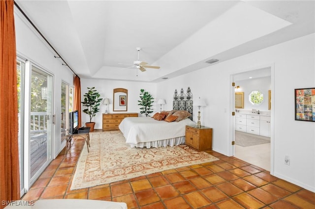 tiled bedroom featuring access to exterior, a tray ceiling, ensuite bath, and ceiling fan