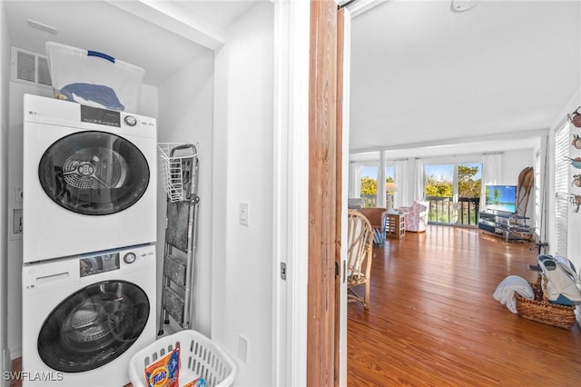 washroom with hardwood / wood-style flooring and stacked washer / dryer