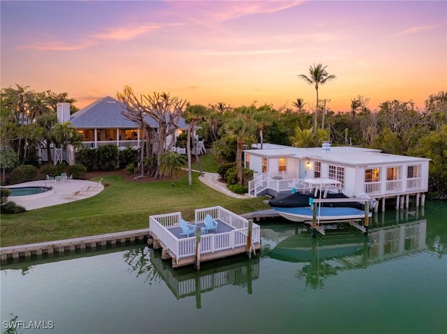 dock area featuring a pool side deck with water view and a yard