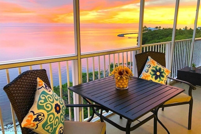 balcony at dusk featuring a water view