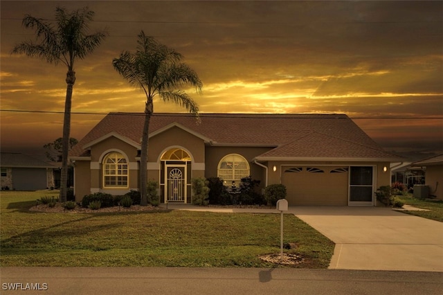 view of front of house with central air condition unit, stucco siding, concrete driveway, a lawn, and a garage