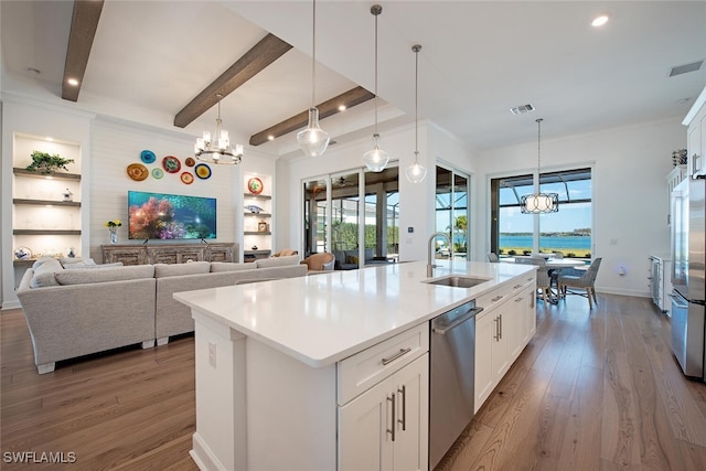 kitchen with sink, appliances with stainless steel finishes, a kitchen island with sink, white cabinetry, and decorative light fixtures