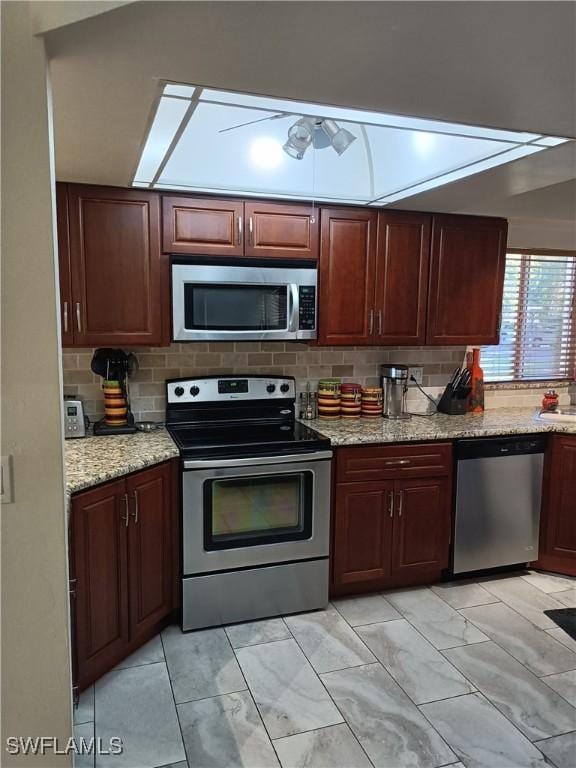 kitchen featuring light stone counters, stainless steel appliances, and backsplash