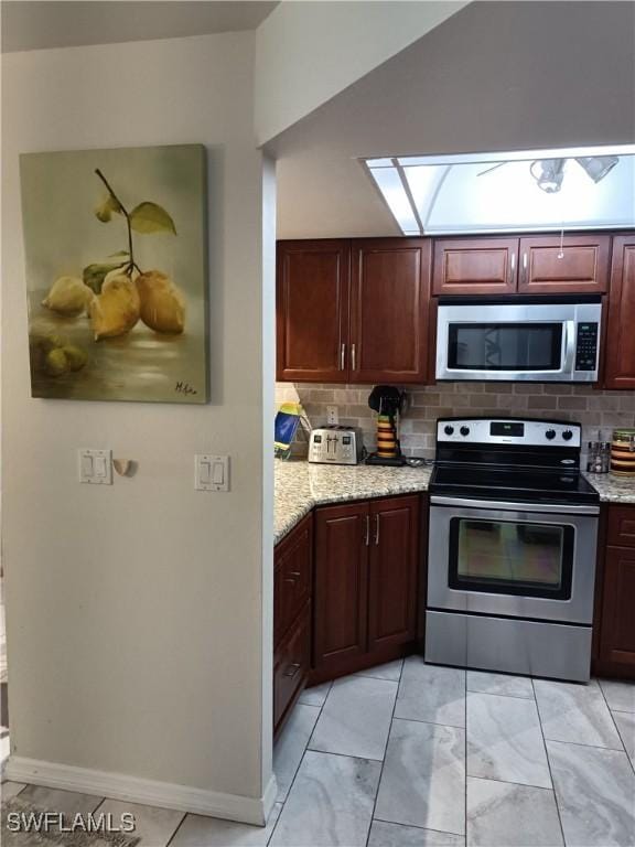 kitchen with tasteful backsplash, lofted ceiling, light stone countertops, and appliances with stainless steel finishes