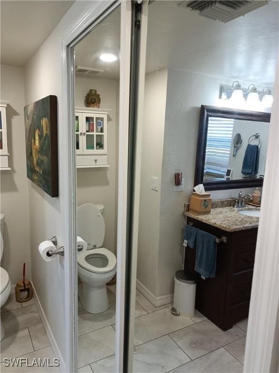 bathroom featuring vanity, tile patterned floors, and toilet