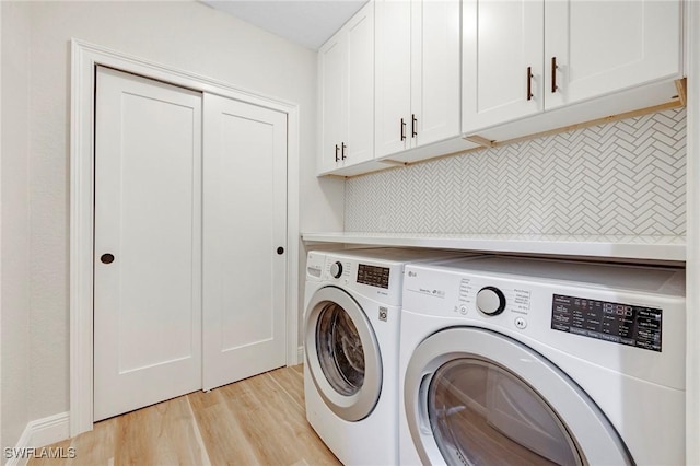 laundry room with separate washer and dryer, cabinet space, and light wood-style floors