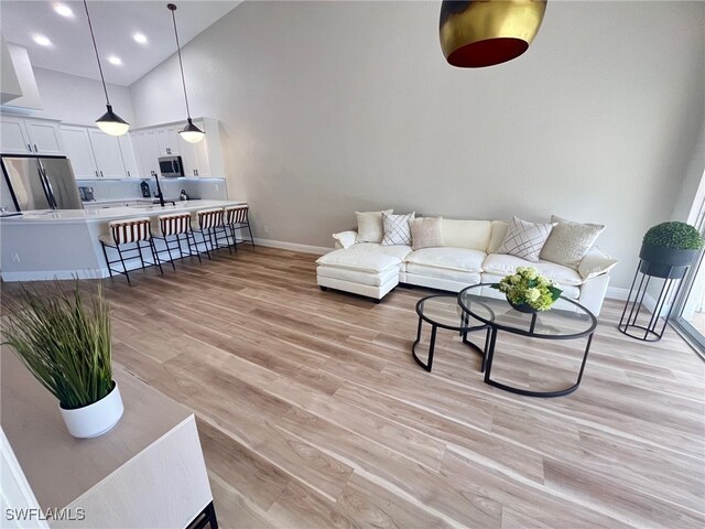 living room with a towering ceiling and light wood-type flooring