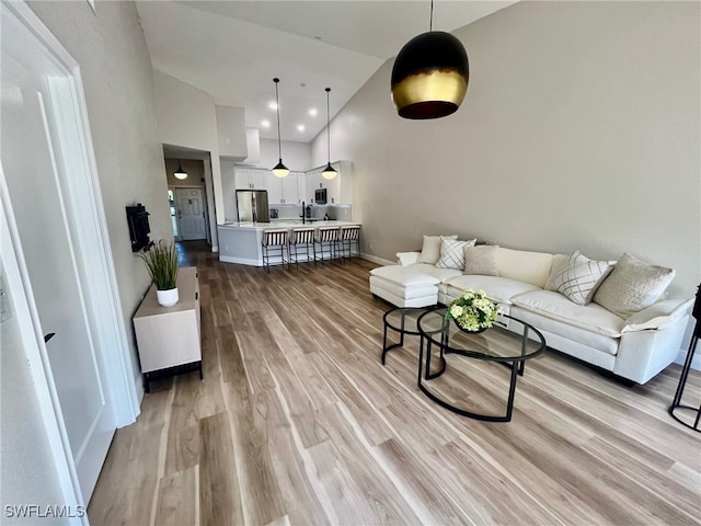 living area with high vaulted ceiling, recessed lighting, wood finished floors, and baseboards