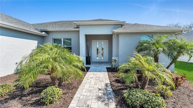 property entrance with french doors, roof with shingles, and stucco siding