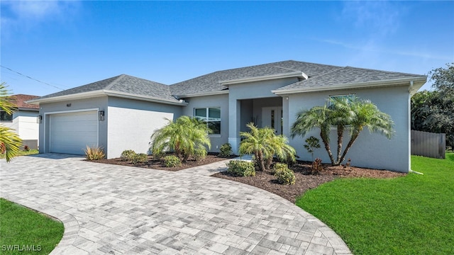 ranch-style home with a garage, decorative driveway, a shingled roof, and a front lawn