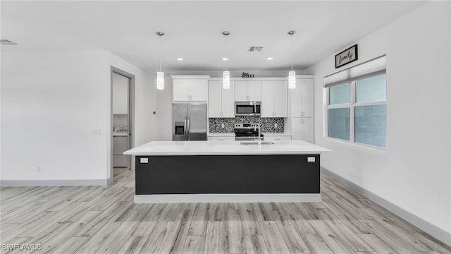 kitchen with tasteful backsplash, a center island with sink, visible vents, white cabinets, and appliances with stainless steel finishes