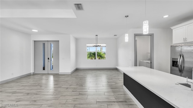 kitchen with visible vents, decorative light fixtures, independent washer and dryer, white cabinetry, and stainless steel refrigerator with ice dispenser