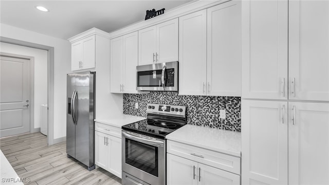 kitchen with tasteful backsplash, white cabinets, light wood-style flooring, stainless steel appliances, and light countertops