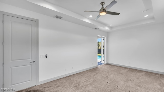 unfurnished room with carpet floors, a tray ceiling, recessed lighting, visible vents, and baseboards