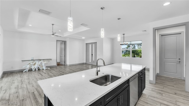 kitchen with a raised ceiling, open floor plan, a sink, dark cabinets, and dishwasher