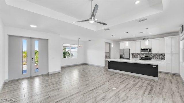 kitchen with visible vents, light countertops, appliances with stainless steel finishes, a tray ceiling, and tasteful backsplash