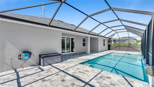 outdoor pool featuring glass enclosure, a ceiling fan, and a patio