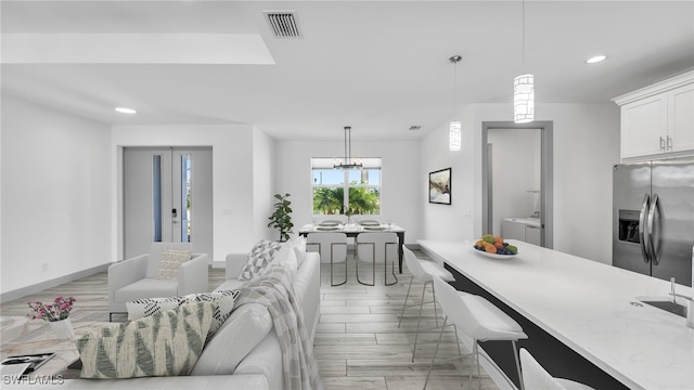 kitchen with visible vents, washer and clothes dryer, stainless steel fridge with ice dispenser, hanging light fixtures, and white cabinetry