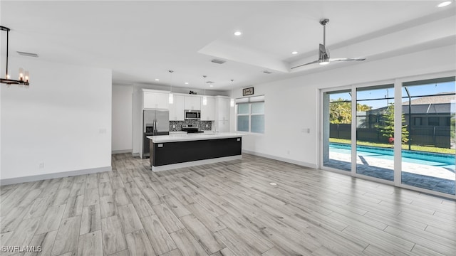 kitchen featuring appliances with stainless steel finishes, light countertops, backsplash, and open floor plan