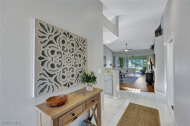 hallway with lofted ceiling and light tile patterned floors