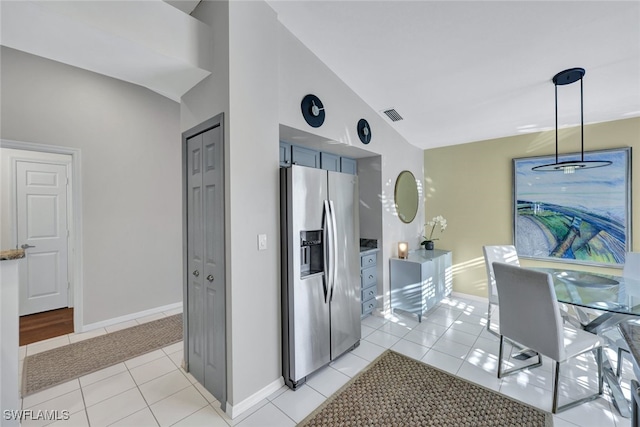 kitchen featuring vaulted ceiling, decorative light fixtures, light tile patterned floors, and stainless steel fridge with ice dispenser