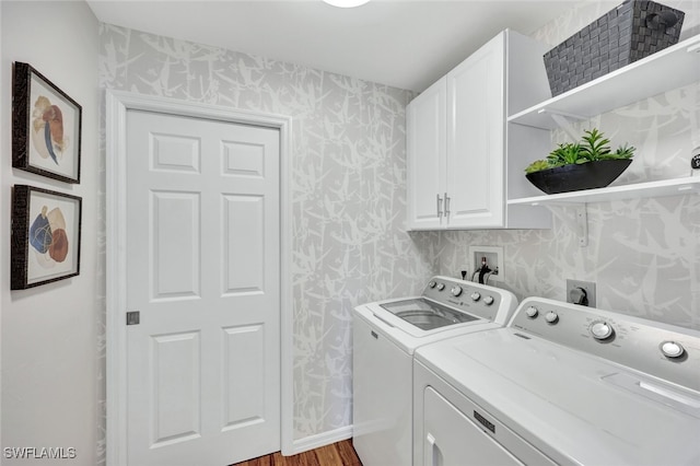 laundry area featuring cabinets, washer and clothes dryer, and light hardwood / wood-style flooring