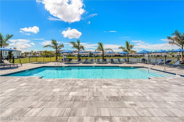 community pool with a patio area and fence