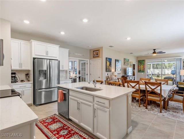 kitchen featuring open floor plan, a sink, light countertops, stainless steel appliances, and backsplash