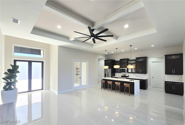 kitchen with a breakfast bar area, hanging light fixtures, coffered ceiling, a center island with sink, and french doors