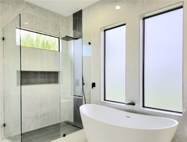 bathroom featuring plus walk in shower and tile walls