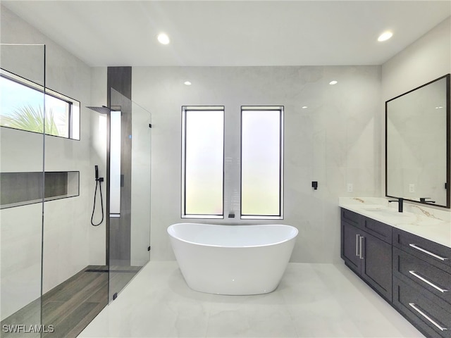 bathroom featuring vanity, independent shower and bath, and tile walls