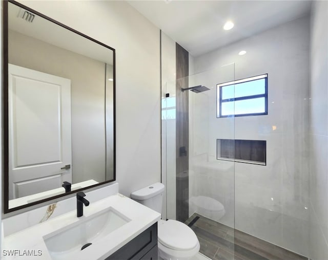 bathroom featuring vanity, toilet, and a tile shower