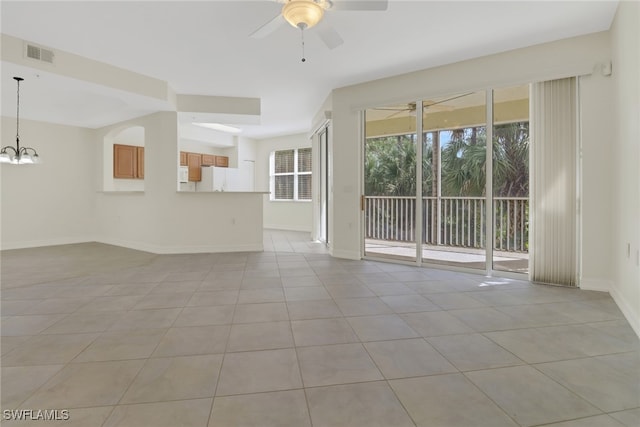 tiled spare room with ceiling fan with notable chandelier