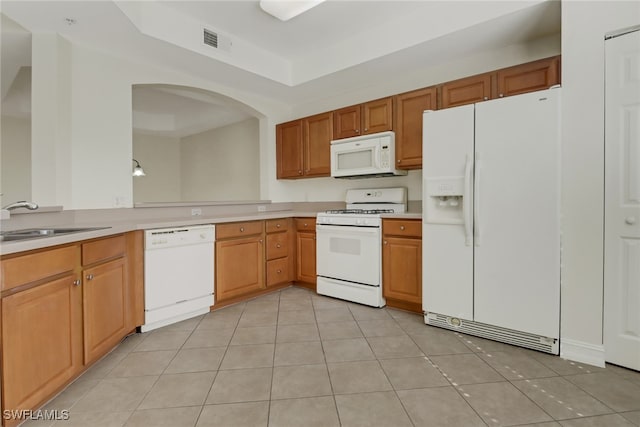 kitchen featuring white appliances, a raised ceiling, sink, and light tile patterned floors