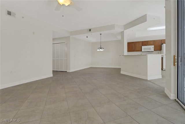 unfurnished living room with ceiling fan with notable chandelier and light tile patterned floors