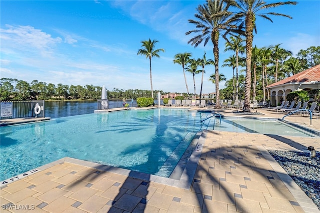 view of swimming pool featuring a patio and a water view