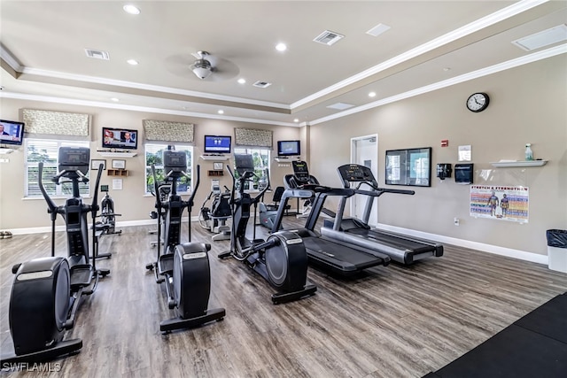 workout area with crown molding, a tray ceiling, wood-type flooring, and ceiling fan