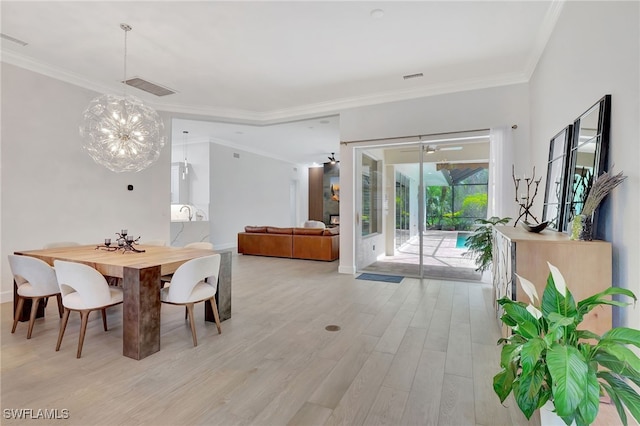 dining room with an inviting chandelier, ornamental molding, and light hardwood / wood-style floors