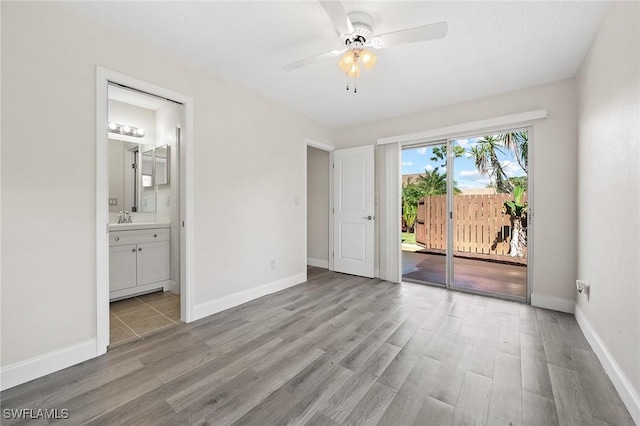 unfurnished bedroom featuring light wood-type flooring, access to exterior, baseboards, and a sink