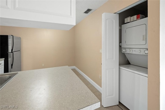 washroom with visible vents, laundry area, stacked washer and clothes dryer, and baseboards