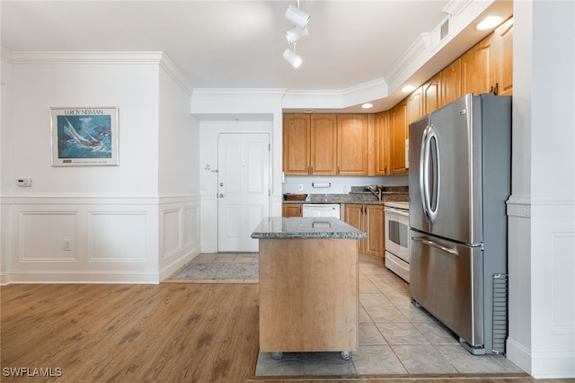 kitchen featuring a kitchen island, white appliances, crown molding, track lighting, and light wood-type flooring