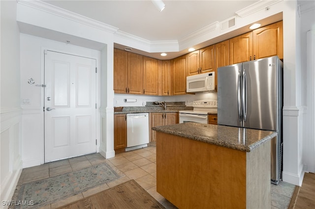 kitchen with crown molding, a kitchen island, light tile patterned floors, and white appliances